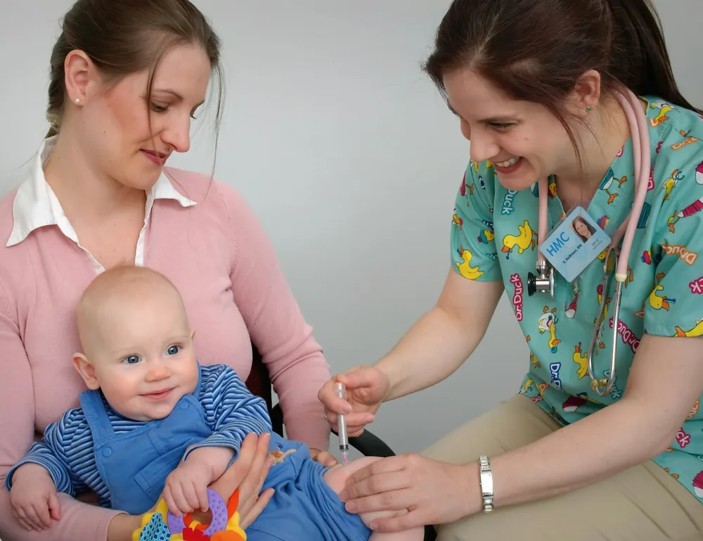 Bebê recebendo vacina no colo da mãe